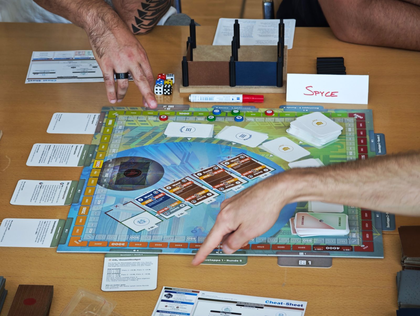 Lernende spielen das Re-Use Game am Spielbrett, daneben das 3D-Modell